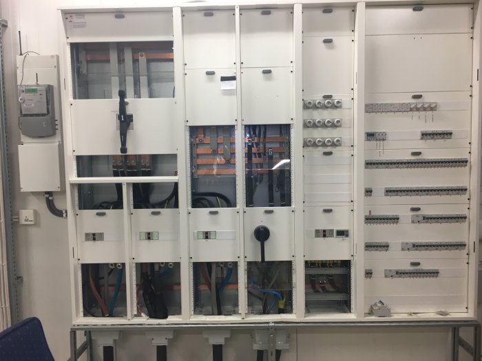 Öppet elskåp med synliga kopparledningar och komponenter, samt tecken på möjlig skada eller felinstallation.