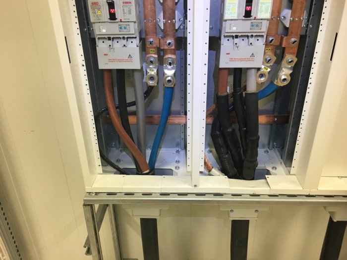 Öppen elcentral med kablar, kopparskenor, och olika komponenter, som visar tecken på potentiellt slarvig installation.
