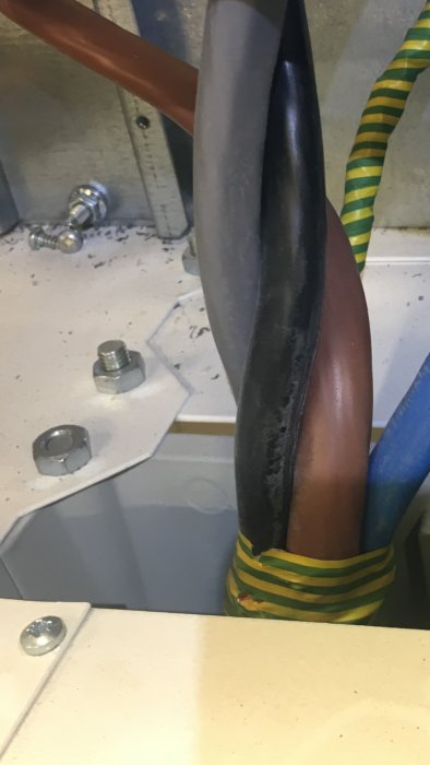 Skadad isolering på svart kabel och synliga anslutningsdetaljer inuti elcentral.