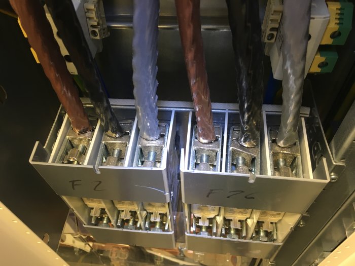 Översikt av en elcentral med kopparledningar som är anslutna till elektromekaniska komponenter märkta "F2" och "F26".