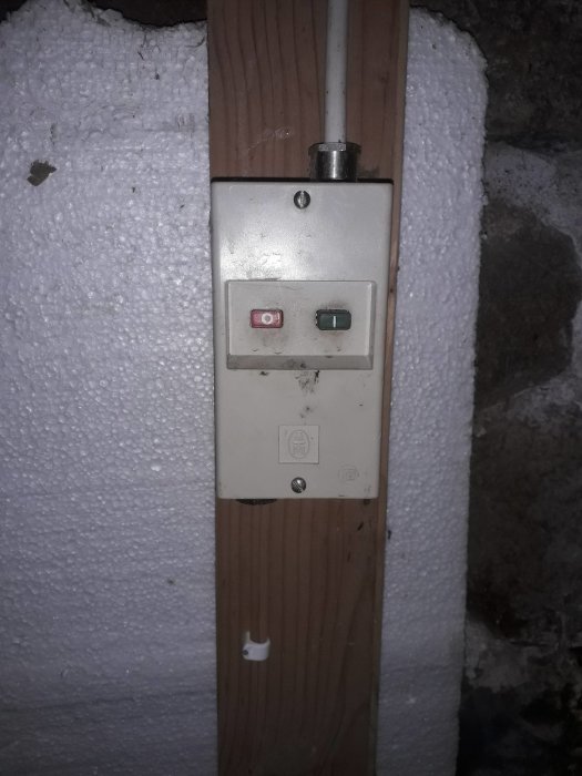 Bild på en gammal strömbrytare till en hydroforpump monterad på en trälist.