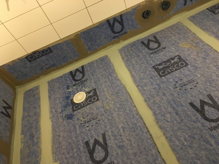 Färdiginstallerade tätskikt och Purus-brunnar på ett badrumsgolv före klinkerläggning.