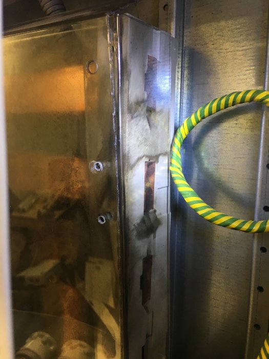 Elcentral med skadat beröringsskydd och sotspår som indikerar överslag nära monteringsskruvar.
