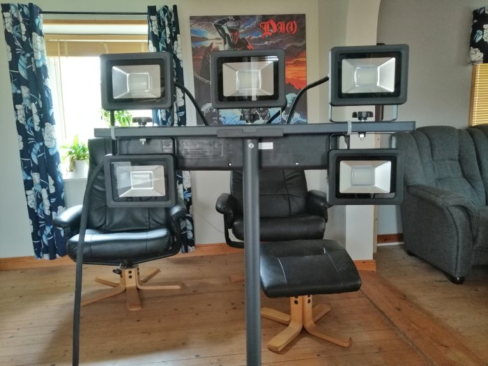 Fyra riktbara lampor monterade på ett svart stativ i ett vardagsrum med en förgreningsdosa på baksidan.