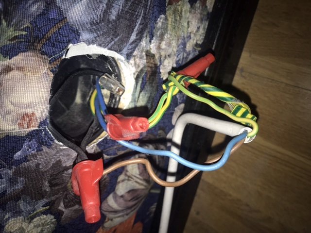 Eloberoende elinstallation med öppna kablar i färger brun, blå, gul/grön i en väggdos.