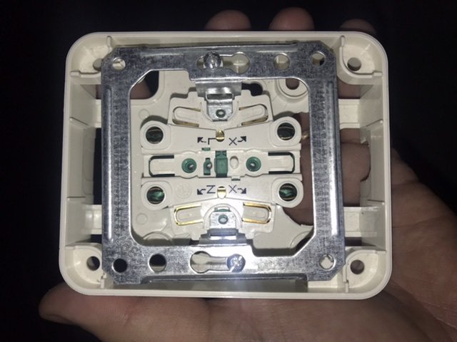 Öppen elektrisk dosa redo för elinstallation med platser för kablar markerade för brun, blå och grön/gul ledning.