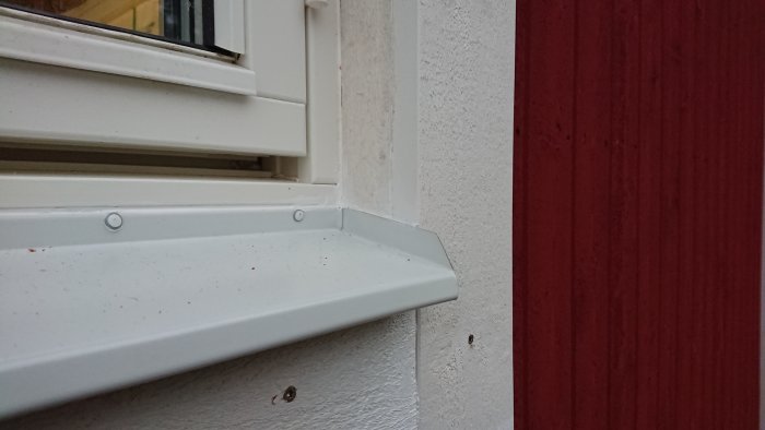 Närbild på nyligen installerat fönsterfoder och fönsterbleck på ett hus under vintern.