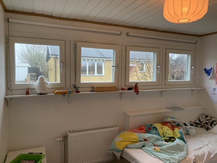 Rum med tre fönster och bred fönsterbräda, inredd barnkammare utan installerade rullgardiner.