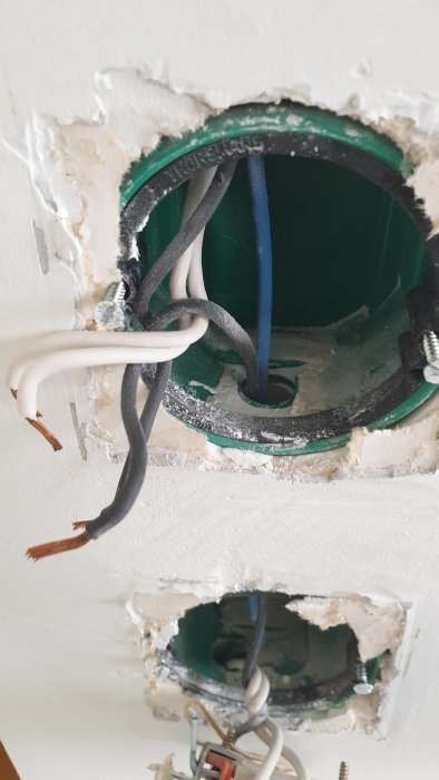 Eluttag under installation med synliga vita och svarta kablar samt grön installationsdosa.