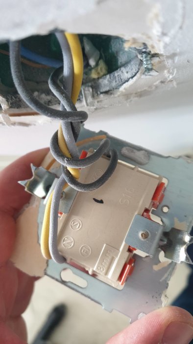Elektriska kablar anslutna felaktigt till ett vägguttag utan täckplatta under installation.