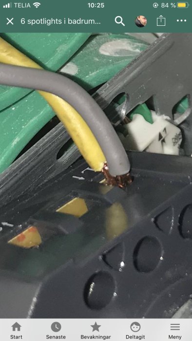 Grå och gul elledning sammanbundna med en skarvklämma i ett elektriskt kopplingsskåp.