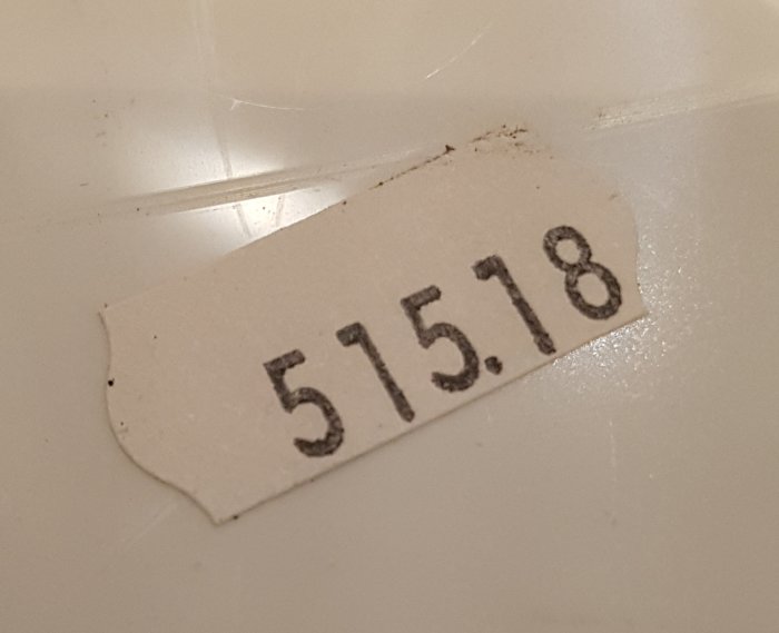 Sliten etikett med numret "515.18" på en vit bakgrund, troligtvis ett datum eller en kod.