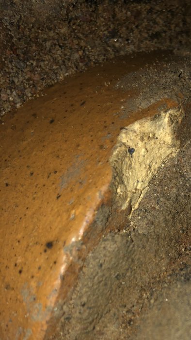 Närbild av en möjlig fukt- eller vattenskada på betongyta i mörkt utrymme.