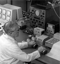 Man utför experiment med elektriska apparater på ett bord i ett gammaldags laboratorium.