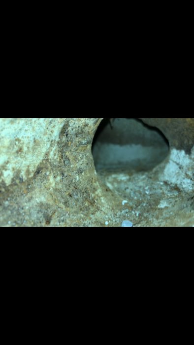 Närbild av rostigt metallrör med synlig korrosion och håligheter.