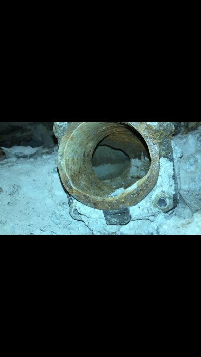 Gammal rostig röranslutning i betongfundament.