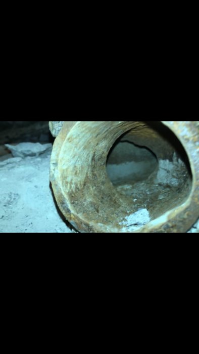 Närbild av en gammal, korroderad rörledning med synliga avlagringar och skadat innerutrymme.