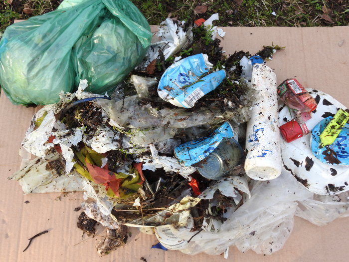 Insamlat skräp som plastflaskor och förpackningar från en dags plockning på landsbygden.