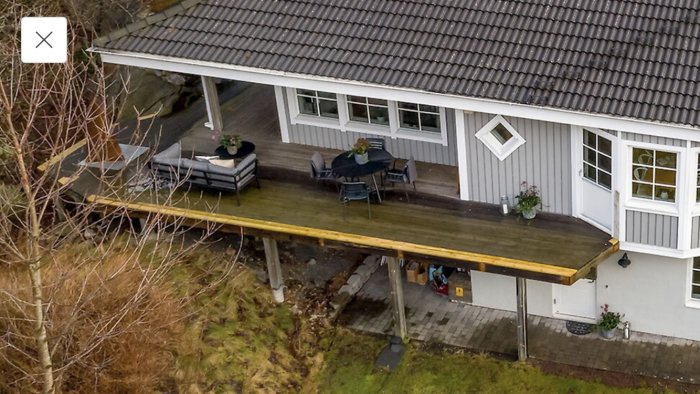 Luften terrass utan räcken vid ett hus, med utemöbler ovanpå, riskabelt för säkerheten.