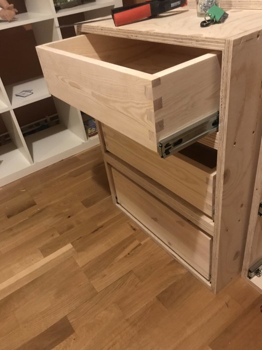 Öppen kökslåda i plywood utan frontpanel, exponerande kortsidan av skivan.