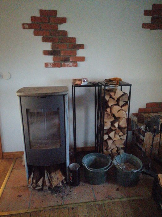 Kamin med stängt glaslock och vedhög, bredvid vedkorgar och skorsten dekorerad med tegel.