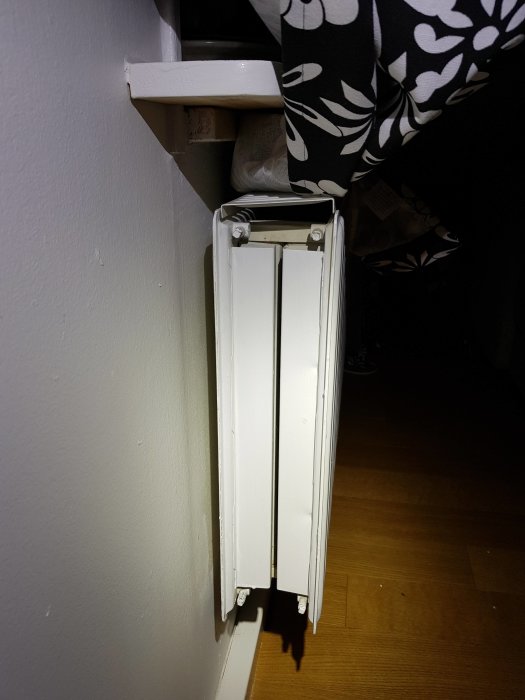 Väggmonterad radiator med övre delen varm och nedre delen kall i ett hemmiljö.
