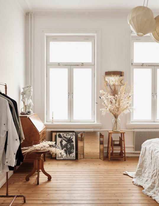 Trägolv med kvistar i ett ljust rum med vita väggar, möbler och inredningsdetaljer.