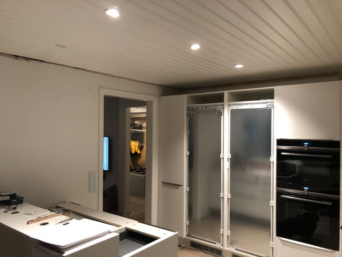 Spotlights i taket i ett pågående köksrenoveringsprojekt, med ljusstråle och halvfärdiga skåp.