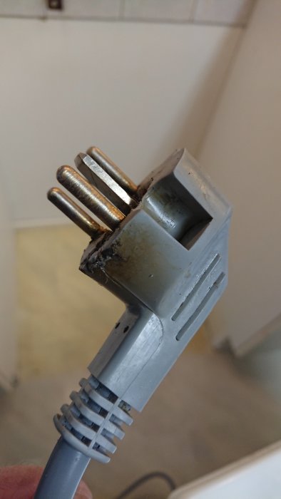 Skadad stickpropp till spis med synliga brännskador och kopplingskabel.