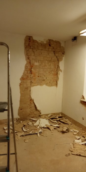 Renoveringsprojekt med exponerad tegelvägg och nedriven puts, byggnadsställning i förgrunden.