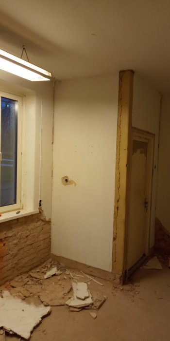 Renoveringsprojekt av ett rum med avslagen puts på tegelvägg, synligt fönster och dörrkarm.