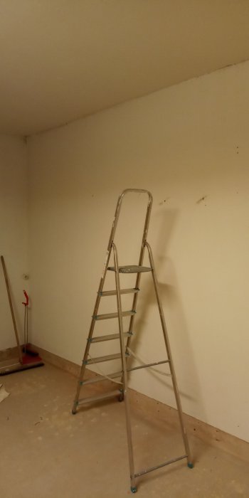 Renoveringsprojekt där en stege står i ett tomt rum med obeklädda väggar och betonggolv.