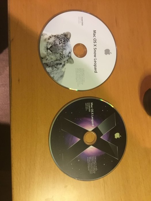 Två CD-skivor med Mac OS X Snow Leopard och Mac OS X Leopard på ett bord.