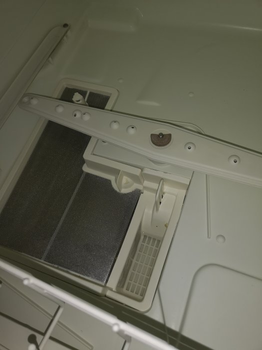 Ren insida på en äldre diskmaskin med synliga filter och silar.