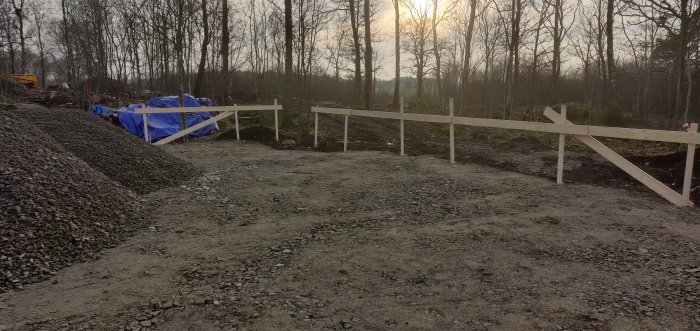 Byggtomt med profiler och spända snören som markerar framtida hus och garageposition.