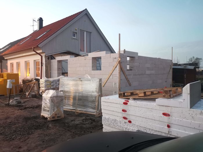 Pågående bygge av husgrund med lättbetongblock och byggmaterial framför.