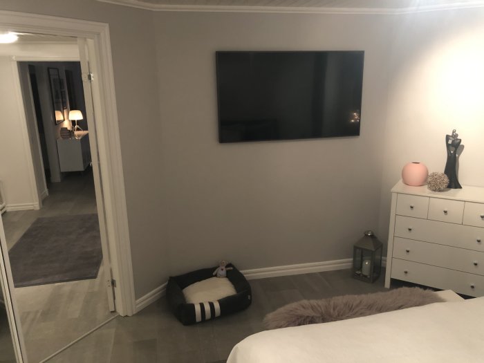 Renoverat sovrum med en stor platt-TV på väggen, nya läslampor och elegant heminredning.