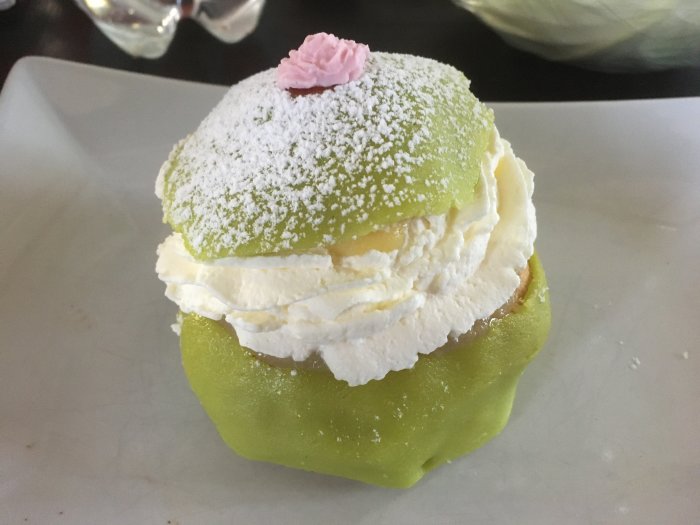 Prinsessemla med sockerkaka, vaniljkräm, marsipan, sylt och grädde på en vit tallrik, pudrad med florsocker.
