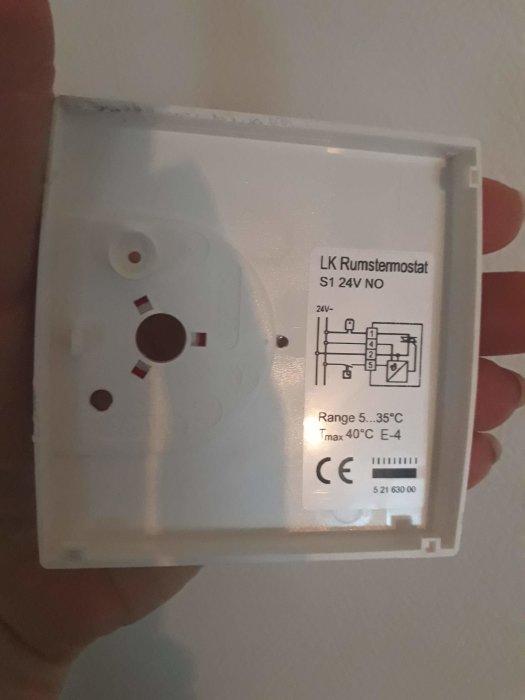 Hand håller en LK S1 rumstermostat för golvvärme med tekniska specifikationer synliga.