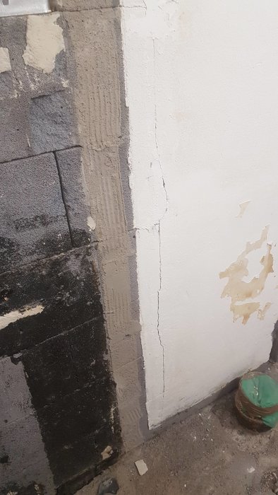 Vägg med delvis borttaget ytskikt som avslöjar underliggande lättbetong med sprickor och ojämnheter.