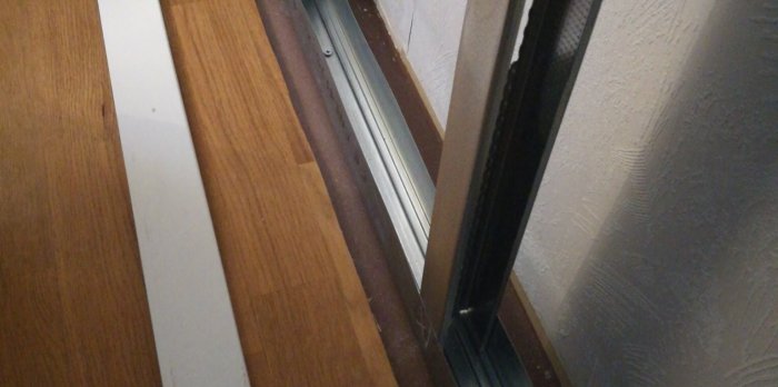Detailjstudie av en nyinstallerad innervägg av stålreglar placerad 45mm från en gammal träpanelvägg.