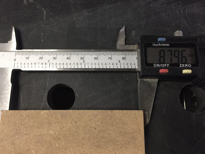 Skjutmått som mäter tjockleken på en sågad träbit, med en visning på 8.96 mm.