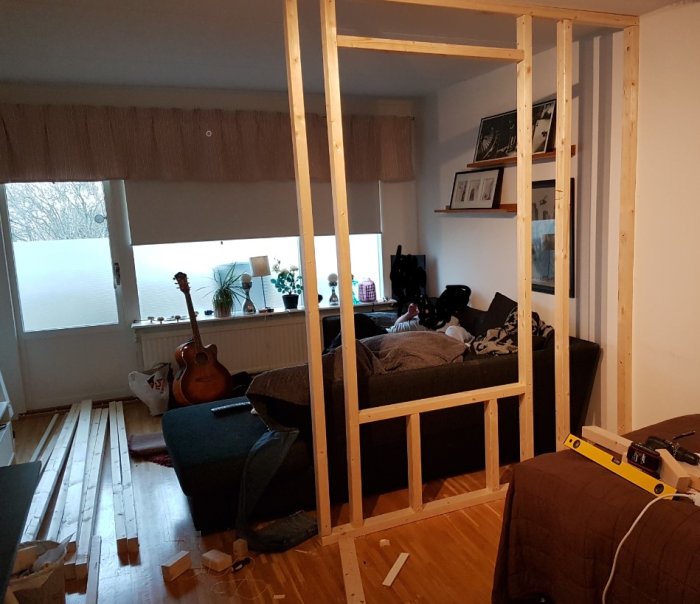 Byggnadsstomme av 45x70 reglar i ett rum med synliga OSBskivor, verktyg och en gitarr.