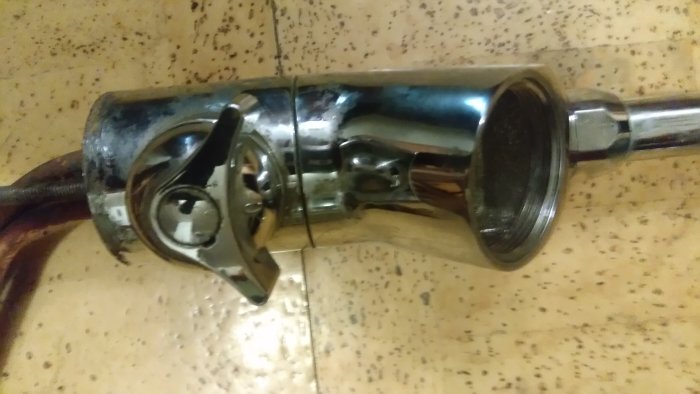 Bild på en avskalad badrumskran monterad på vägg, synliga rör och anslutningar.