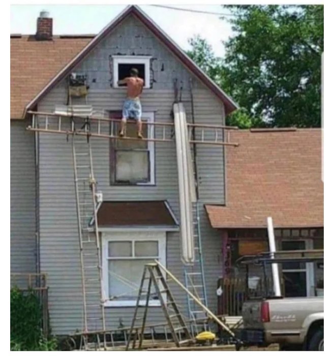 Person på en ovanligt konstruerad ställning framför ett hus under renovering.