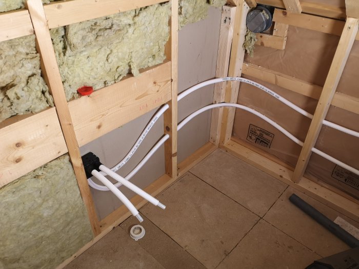 Installation av Uponor pex-rör i ett förberett badrumsutrymme med synlig isolering och spånskivegolv.