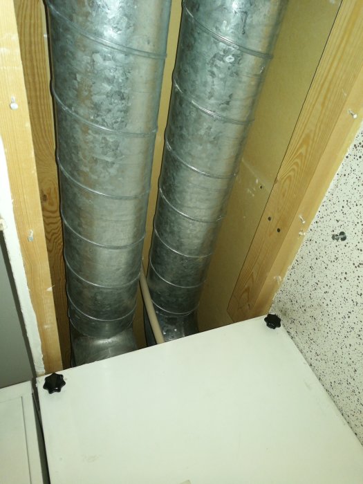 Metallventilationsrör utan ljuddämpning som vibrerar vid beröring i ett hem under renovering.