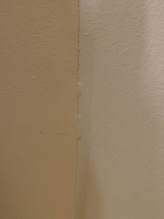 En sprickbildning på målad vägg som uppstått efter ytskiktsrenovering.