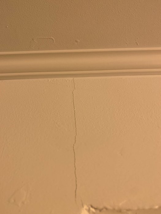 Spricka i vägg vid taklist efter ytskiktsrenovering.