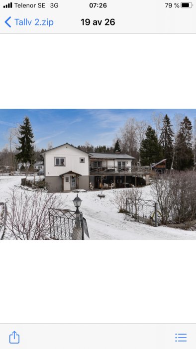 Tvåvåningshus med tillbyggd veranda i ett snöbeklätt landskap.